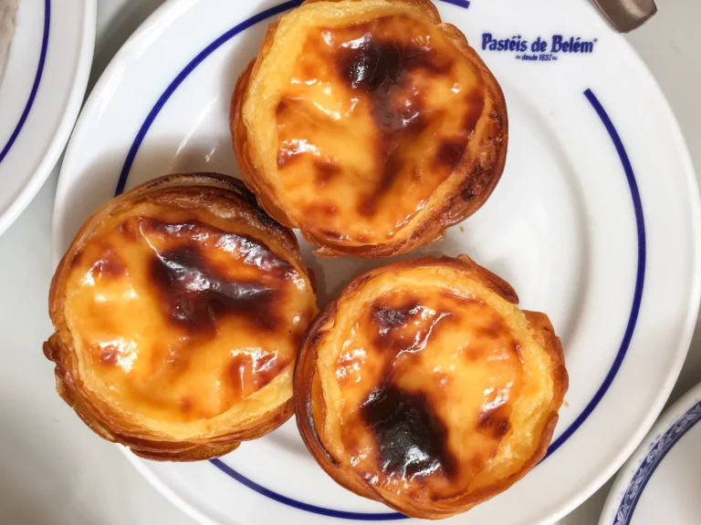 Três pastéis de Belém num prato branco e azul