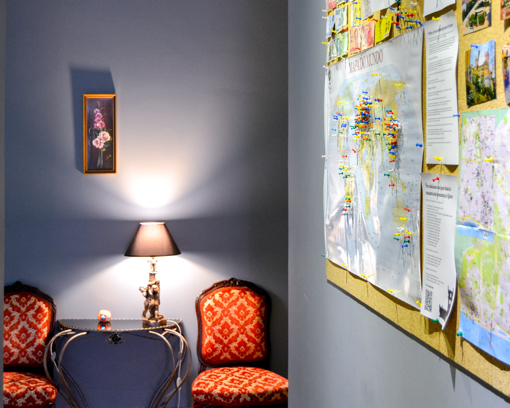 Canto do Ambiente Hostel com cadeiras vermelhas, candeeiro e mapa dos viajantes